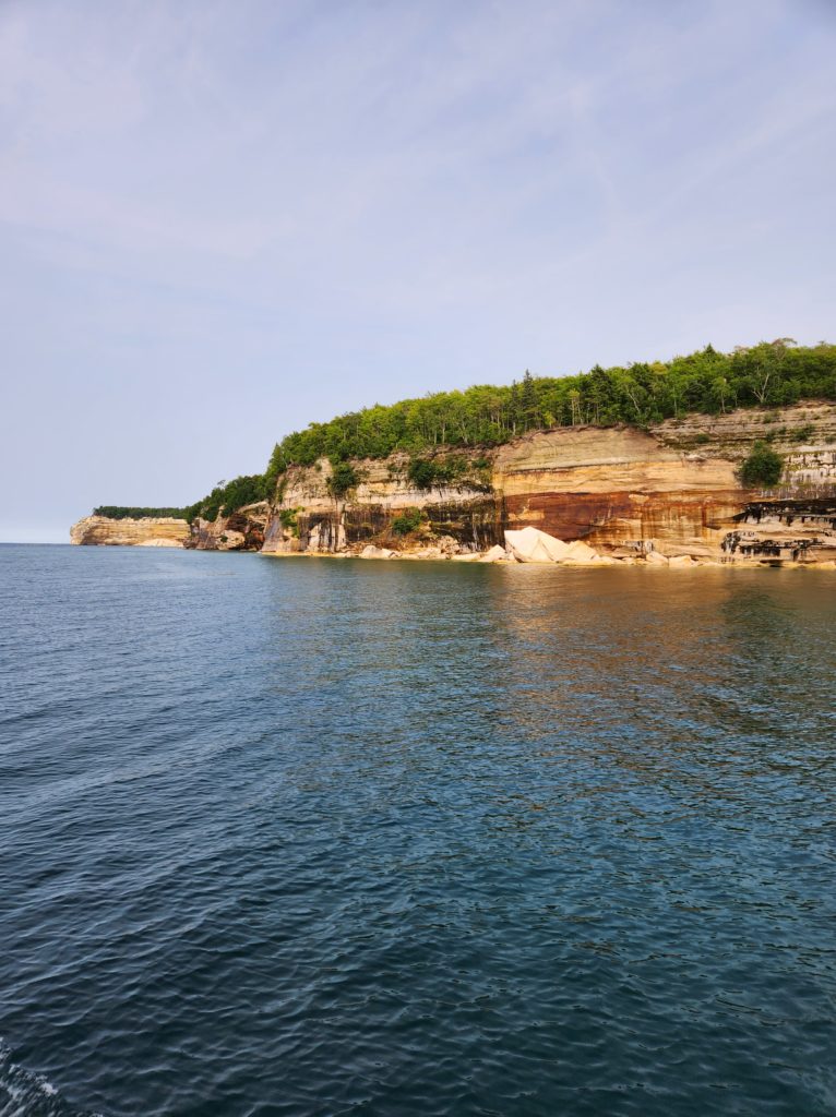 A view of the rock wall at Pictured Rocks National Lakeshore. Blue sky above and Lake Superior all around. 