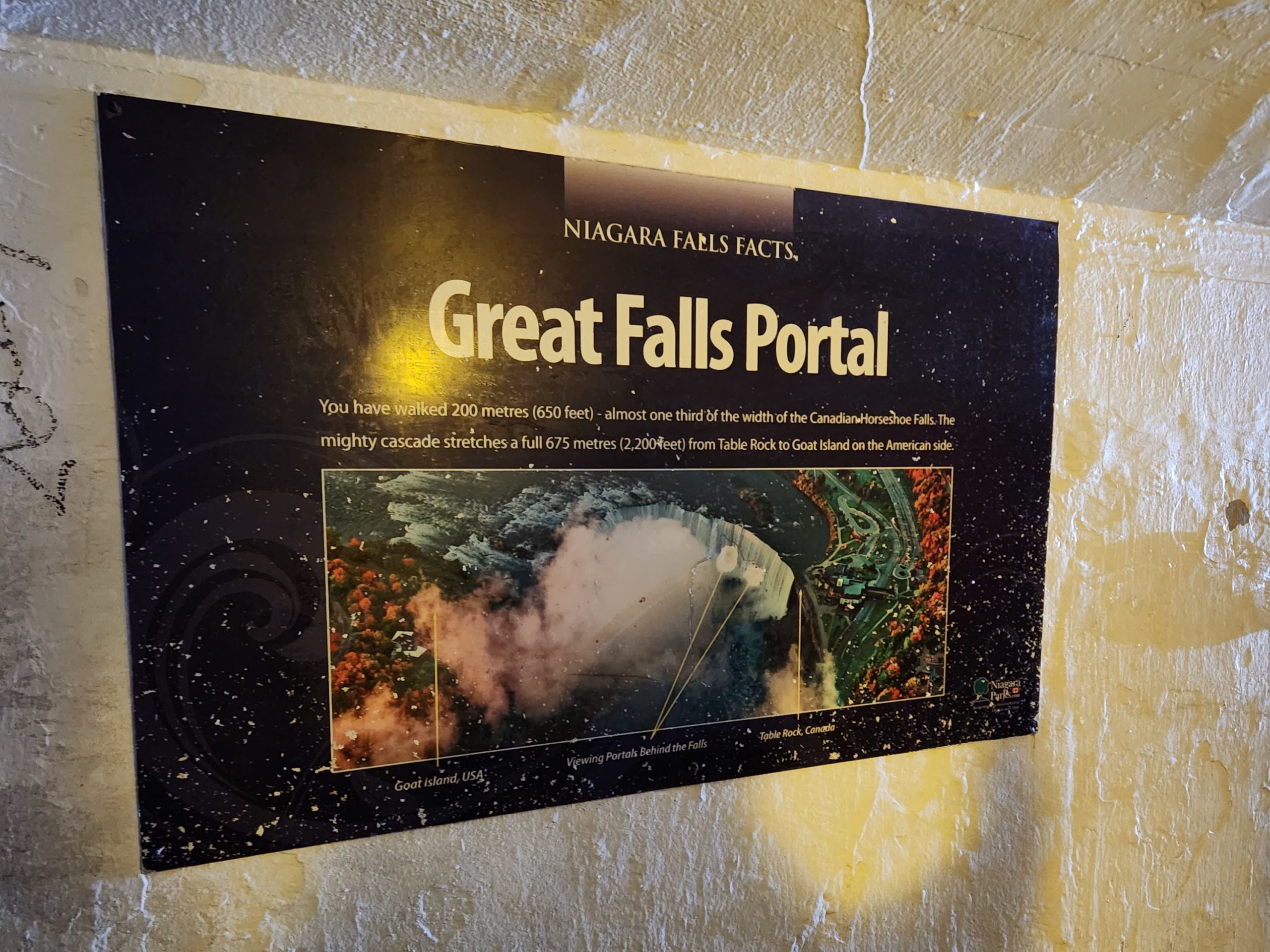 A sign posted on a concrete wall that reads "Great Falls Portal" This is in the Journey Behind the Falls tour in Canada.