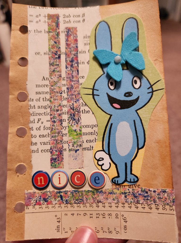 A 3x5 piece of paper with a mixed media collage on it. Different vintage book pages make up the background, while a cartoon bunny stands along the right side. The word "nice" is next to the bunny's feet.