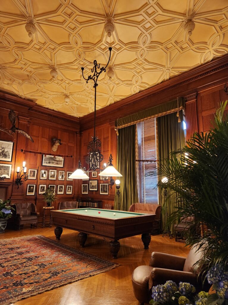 A pool table sitting in the middle of a large, ornately decorated room. 