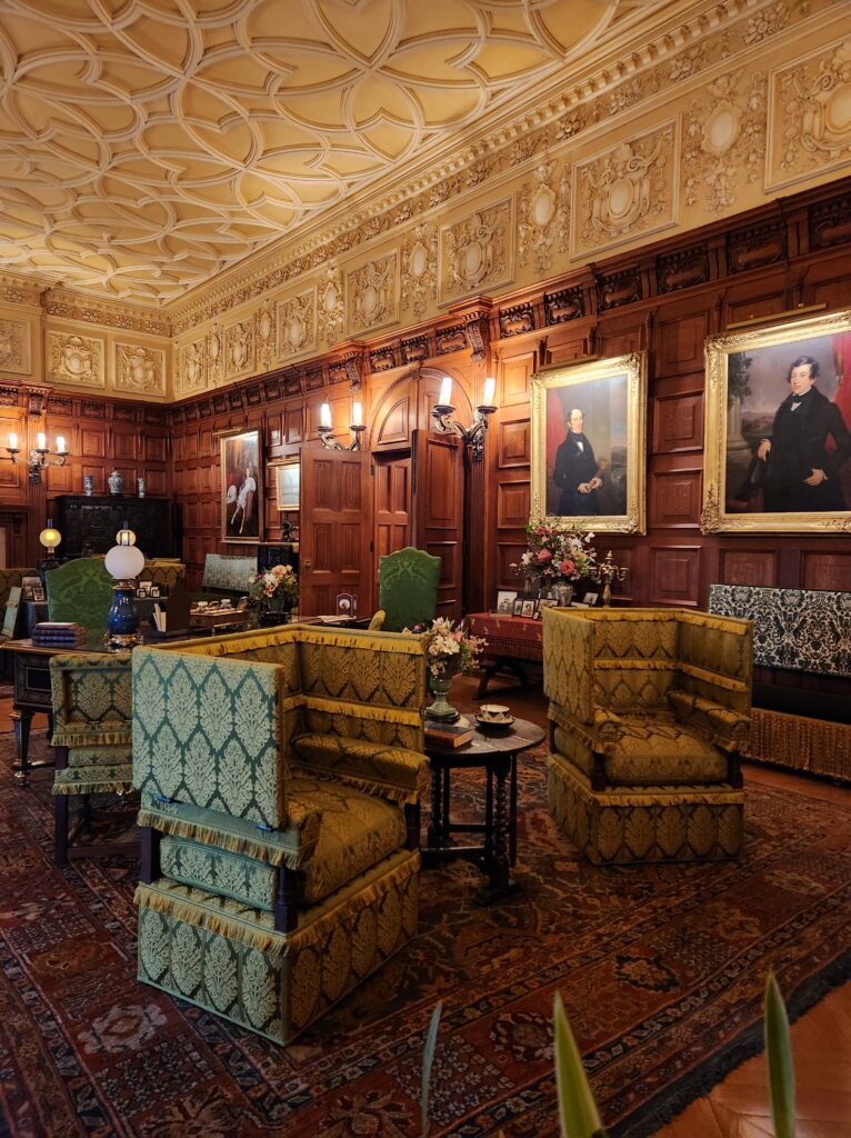 A large sitting room at the Biltmore Estate. Several chairs sit around the room, in arrangements to encourage conversations. The walls are decorated with different portraits. 